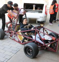 Students help the MIT Motorsports team push their car into Lobby 13 for the 2024 MIT Edgerton Center student showcase. 
